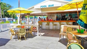 An outdoor pool bar with yellow umbrellas, wicker furniture, and a clear view of the pool in the background. - The Little Oasis Beach House (Captiva)