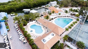 A resort with a large swimming pool, a smaller pool, and a dock with boats. - The Little Oasis Beach House (Captiva)