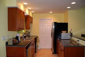 A compact kitchen with wooden cabinets, a microwave, and a sink.