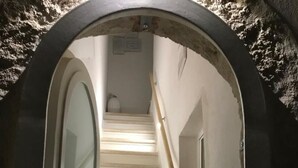 A staircase with a glass door on the left and a wooden handrail on the right, leading to an upper floor. - Romì (Polignano a Mare)