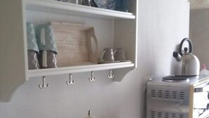 A kitchen with a wooden table, a sink, and shelves with dishes and utensils. - Romì (Polignano a Mare)