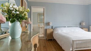 A bedroom with a large bed, a dresser, a vanity with a mirror, and a vase of flowers. - Hexham Town Bed and Breakfast (Hexham)