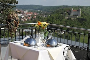Une table dressée pour le dîner, avec vue sur une ville et des collines en arrière-plan.
