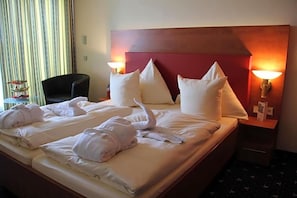 Une chambre d’hôtel avec un lit, des oreillers, une chaise et une table de chevet avec une lampe.
