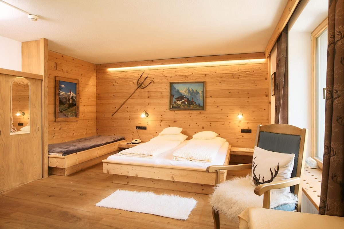Una habitación de madera con una cama, una silla y un banco.