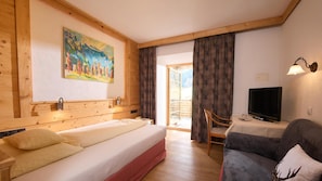 A hotel room with a bed, a television, a sofa, and a painting on the wall.