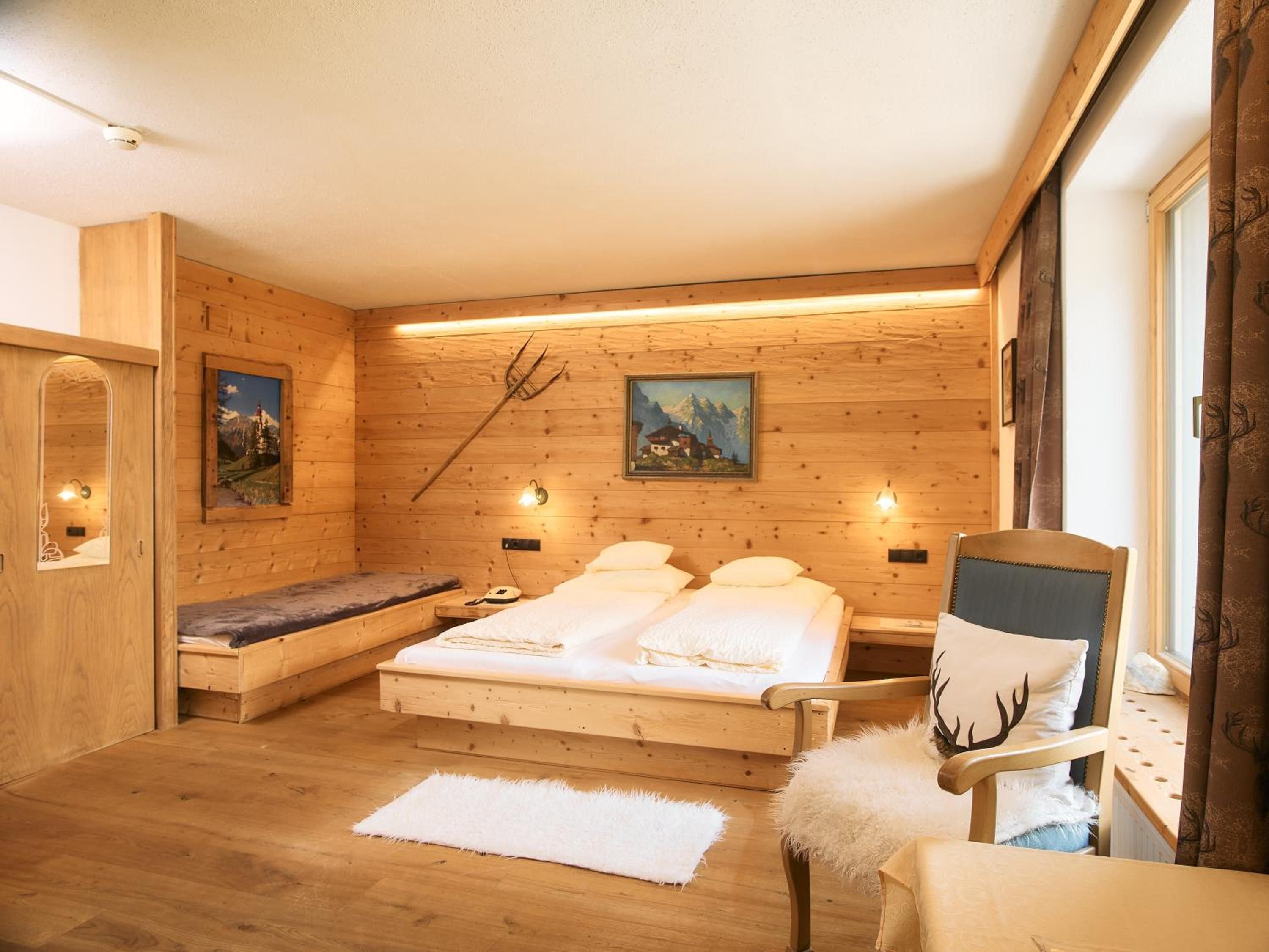 Ein Zimmer mit Holzboden, einem Bett, einem Sessel und einer Bank.