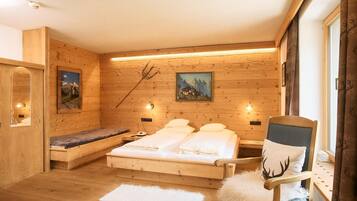 Ein Zimmer mit Holzboden, einem Bett, einem Sessel und einer Bank.