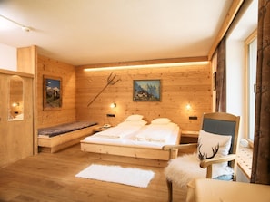 A wooden room with a bed, a chair, and a bench.