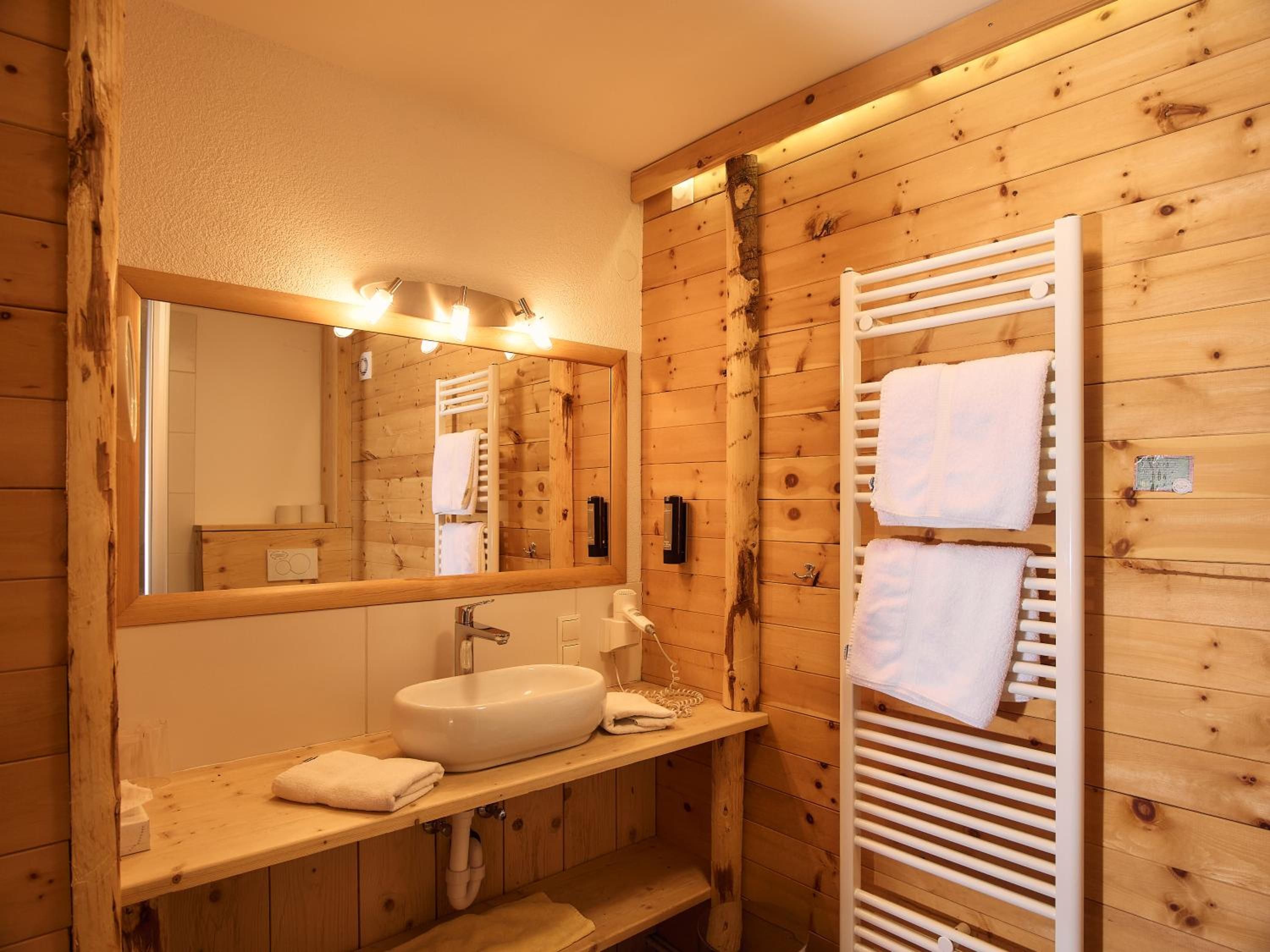 Un bagno in stile baita con ampie finestre, un lavandino e un porta asciugamani.