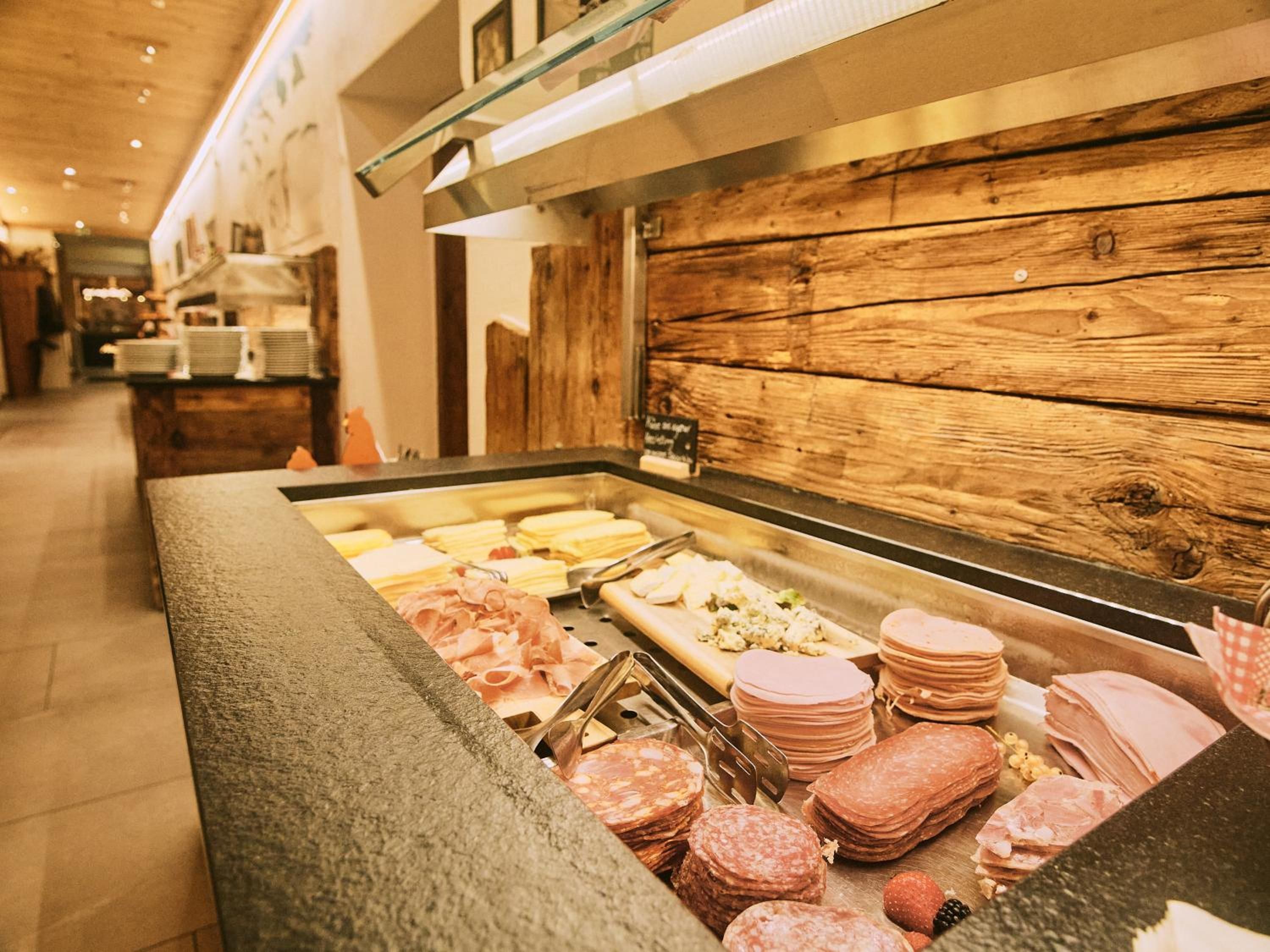 A buffet with various meats and cheeses.