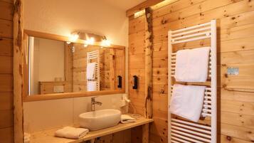 Ein Badezimmer im Holzblockhaus-Stil mit einem großen Spiegel, einem Waschbecken und einem Handtuchhalter.