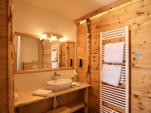 A wooden cabin-style bathroom with a large mirror, a sink, and a towel rack.
