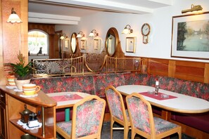 A restaurant with a booth seating area, wooden furniture, and wall-mounted clocks.