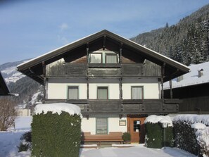 A two-story building with a sloped roof, a wooden facade, and a snow-covered landscape.