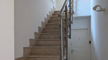 Un escalier avec des marches en bois et des rampes en métal menant à une porte blanche.