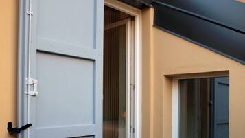 Puerta corredera abierta que da a una habitación con ventana y un pequeño espacio exterior con un tapete verde.