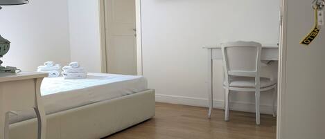 A room with a bed, a desk, a chair, a television, and a door.
