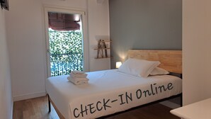 Een slaapkamer met een bed, een raam met uitzicht en een bordje met de tekst 'CHECK-IN Online' op het bed.