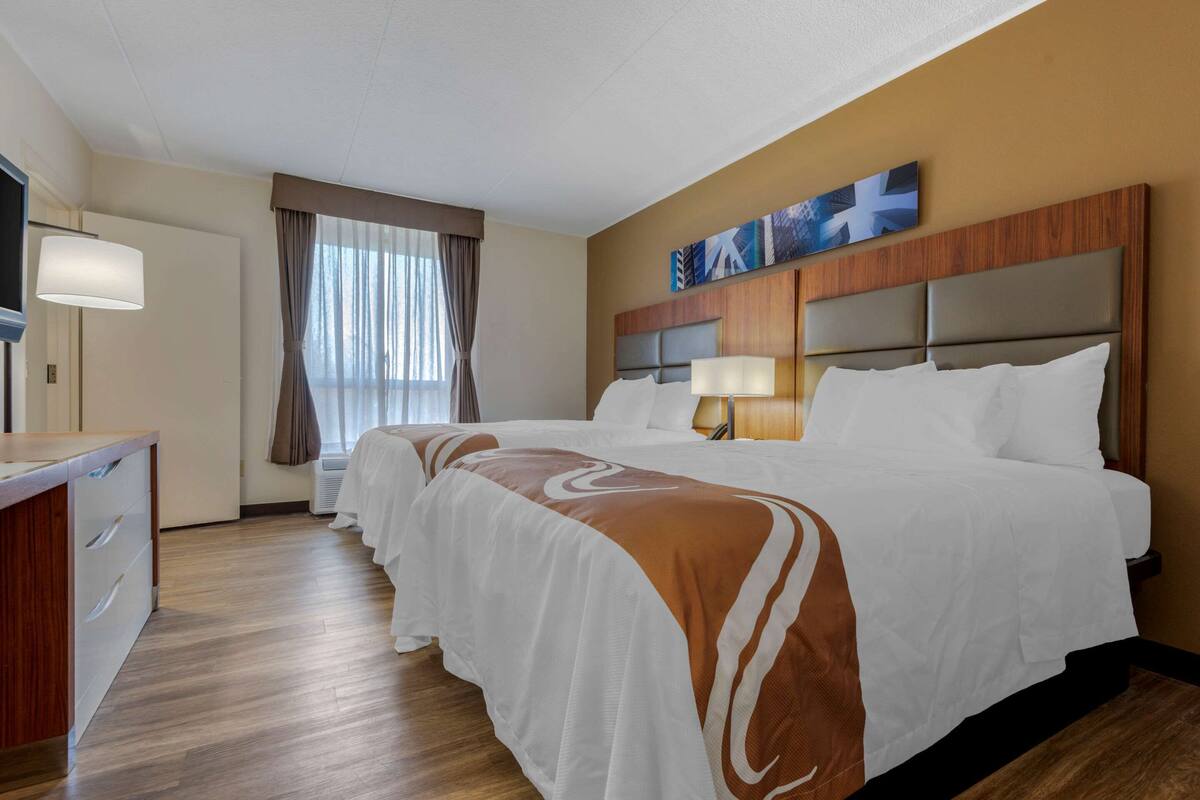 A hotel room with a large bed, a desk, and a television.