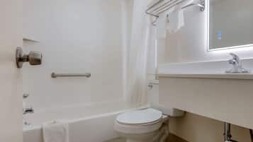 A bathroom with a bathtub, toilet, and a mirror above the sink.