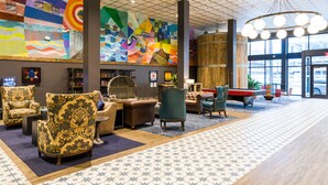 A spacious lobby with a large mural, comfortable seating, a pool table, and a view through the glass doors. - HI New Orleans - Hostel (New Orleans)