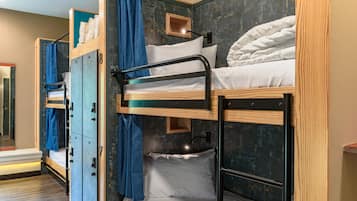 A bunk bed room with a wooden bunk bed, a blue curtain, and a small wooden shelf.