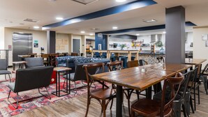 A modern dining area with a wooden table, chairs, and a blue sofa. - HI New Orleans - Hostel (New Orleans)