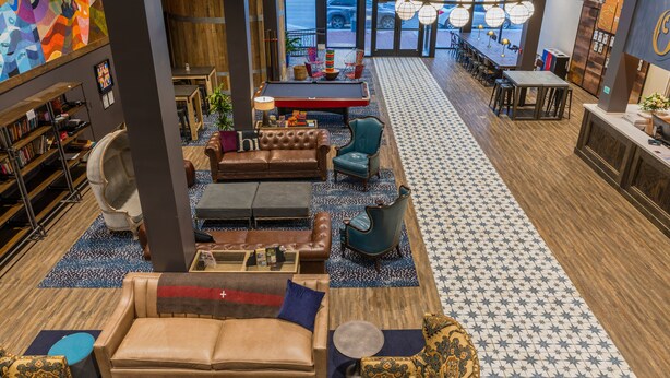 A spacious lobby with leather seating, a pool table, and a bar area. - HI New Orleans - Hostel (New Orleans)