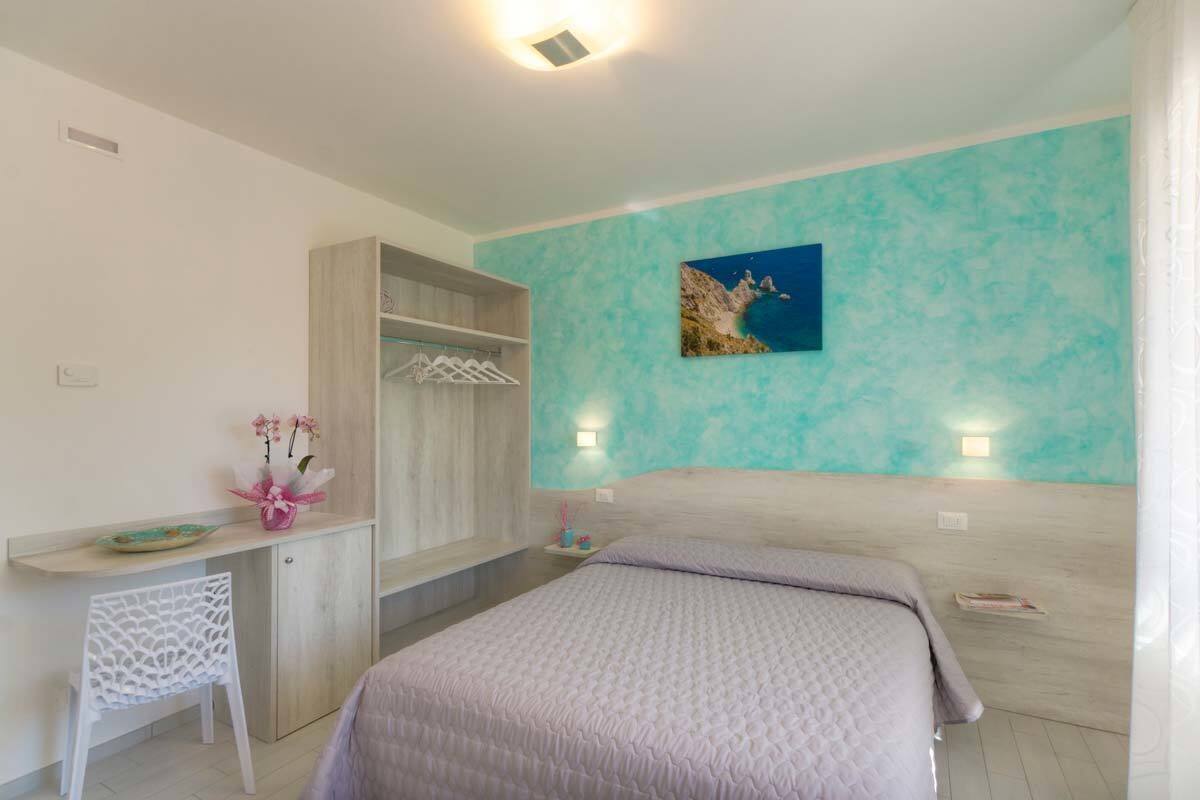Quarto com cama, escrivaninha, cadeira, guarda-roupa e um quadro na parede.