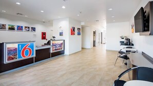 A hotel reception area with a reception desk, a coffee machine, and a seating area. - Motel 6 Channelview, TX (Channelview)