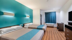 A hotel room with two beds, a flat-screen TV, a desk, and a window with curtains. - Motel 6 Channelview, TX (Channelview)