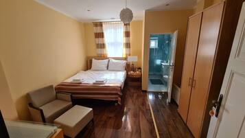 A hotel room with a bed, a chair, a desk, and a wardrobe.