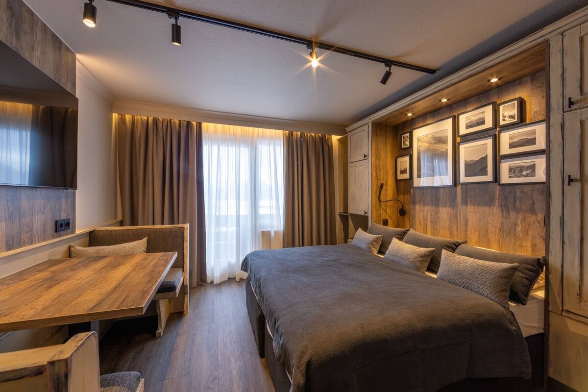 A modern bedroom with a large bed, a wooden bench, and a desk.