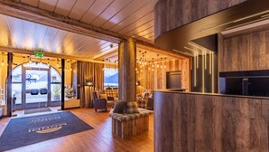Un vestíbulo moderno con suelo de madera, un mostrador de recepción y una zona de estar con vistas a las montañas.