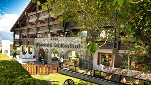 Un edificio de estilo alpino tradicional con múltiples balcones decorados con flores, arcos de piedra y zonas de estar al aire libre.