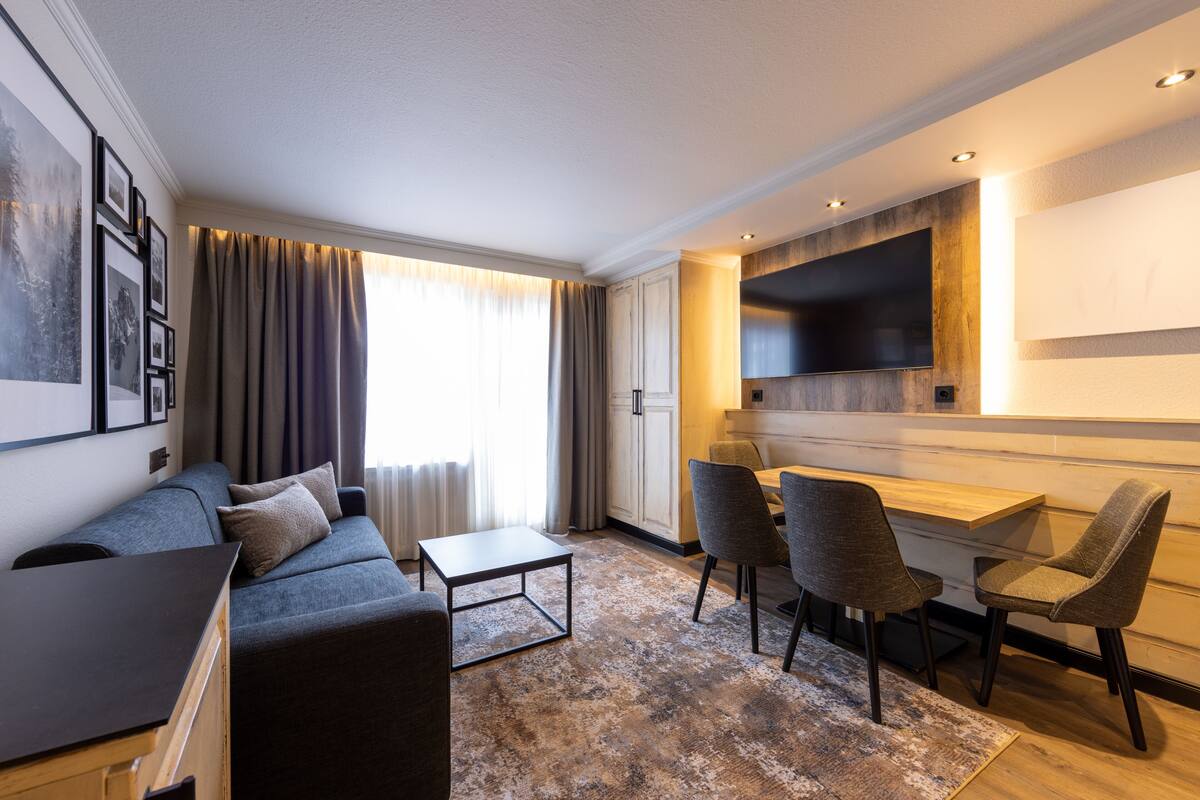 A modern living room with a sofa, a coffee table, and a dining area with chairs.