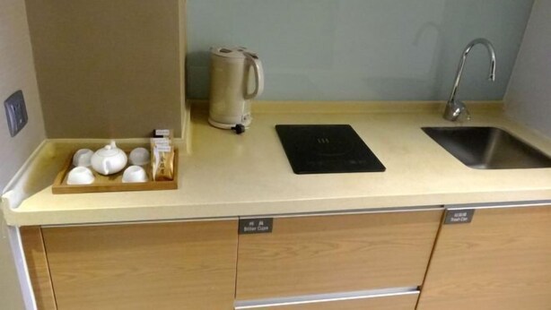 Una cocina compacta con un lavamanos, una tetera y una bandeja con tazas y una cafetera.