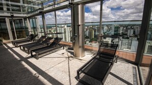 Een dakterras met ligbedden en een panoramisch uitzicht op de stad.