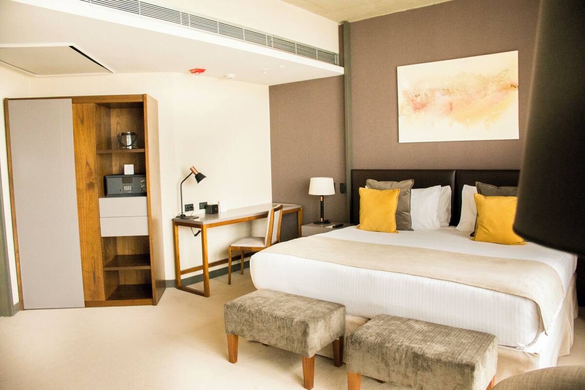 Une chambre d’hôtel avec un grand lit, un bureau, une chaise et une armoire.