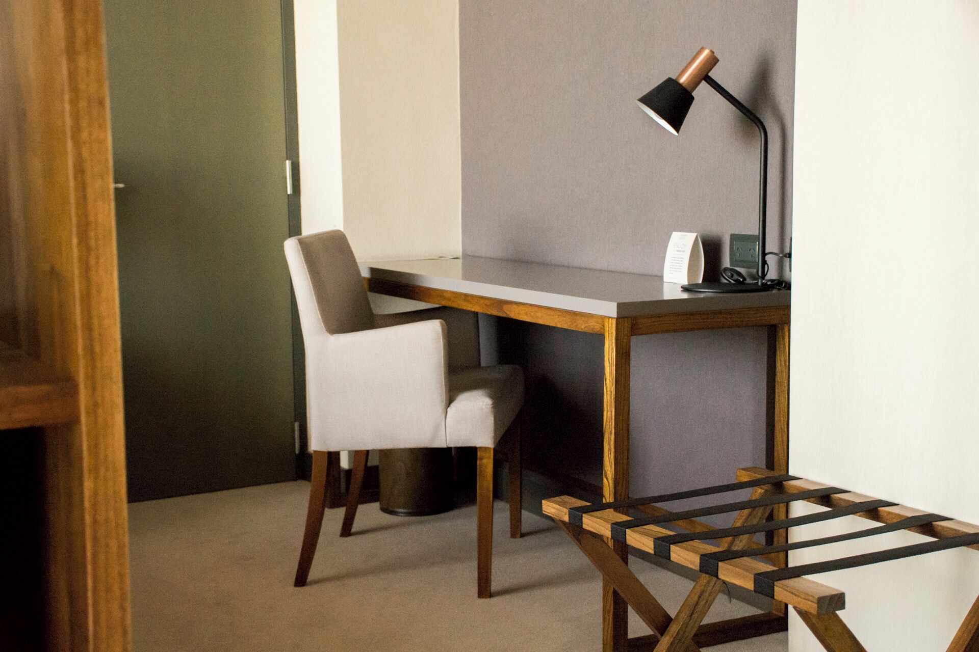 Een kleine, moderne kantoorruimte met een bureau, stoel en lamp.