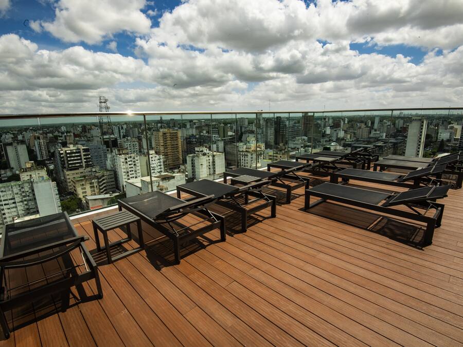 A rooftop terrace with multiple sun loungers and tables, offering a city view.