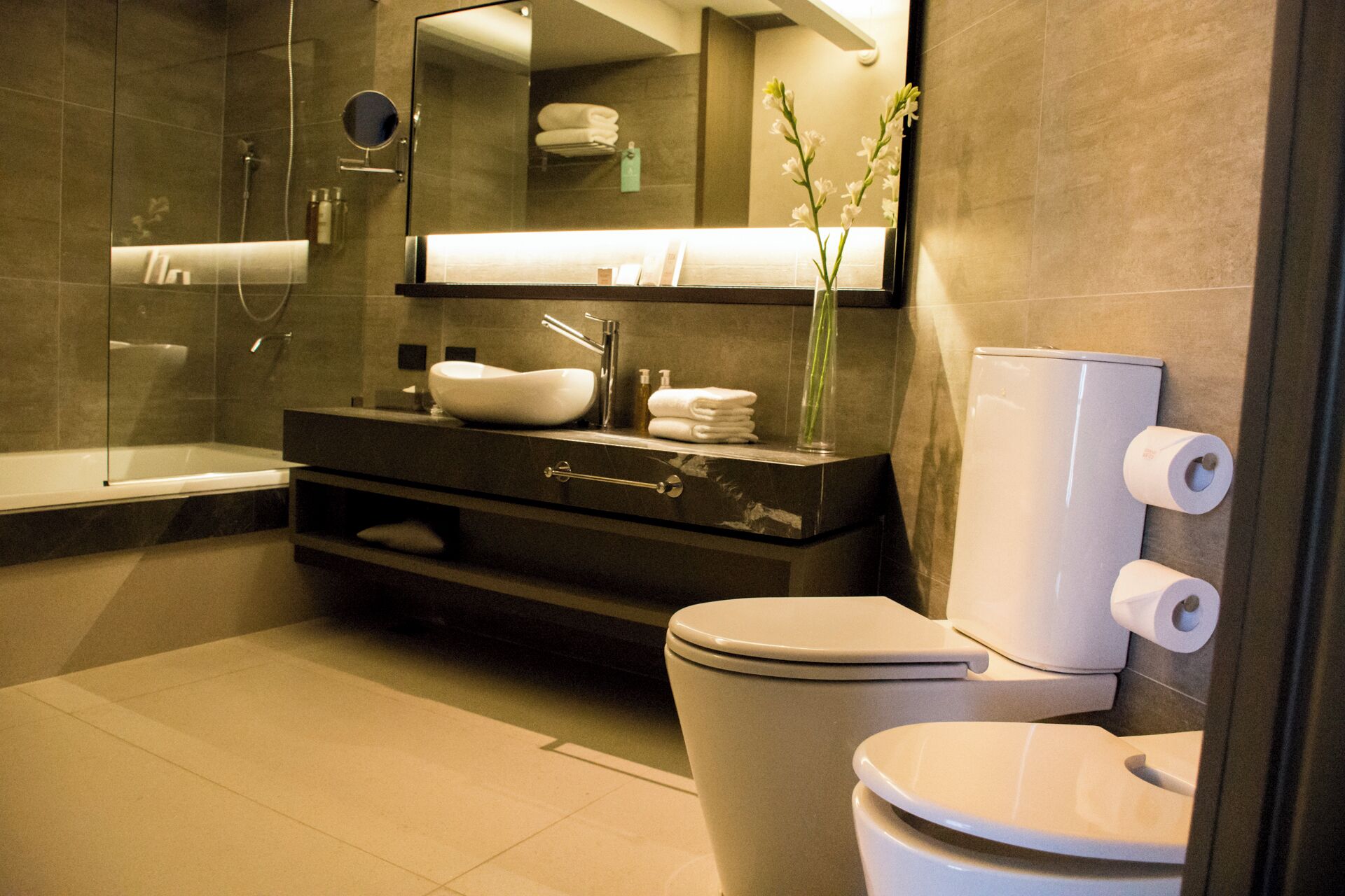 Een moderne badkamer met een bad, een wastafelmeubel met een wastafel, een toilet en een spiegel.