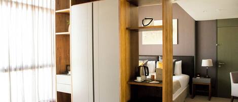 A modern hotel room with a bed, bedside table, lamp, and a wardrobe.