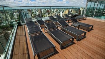 A rooftop terrace with sun loungers and a city view.