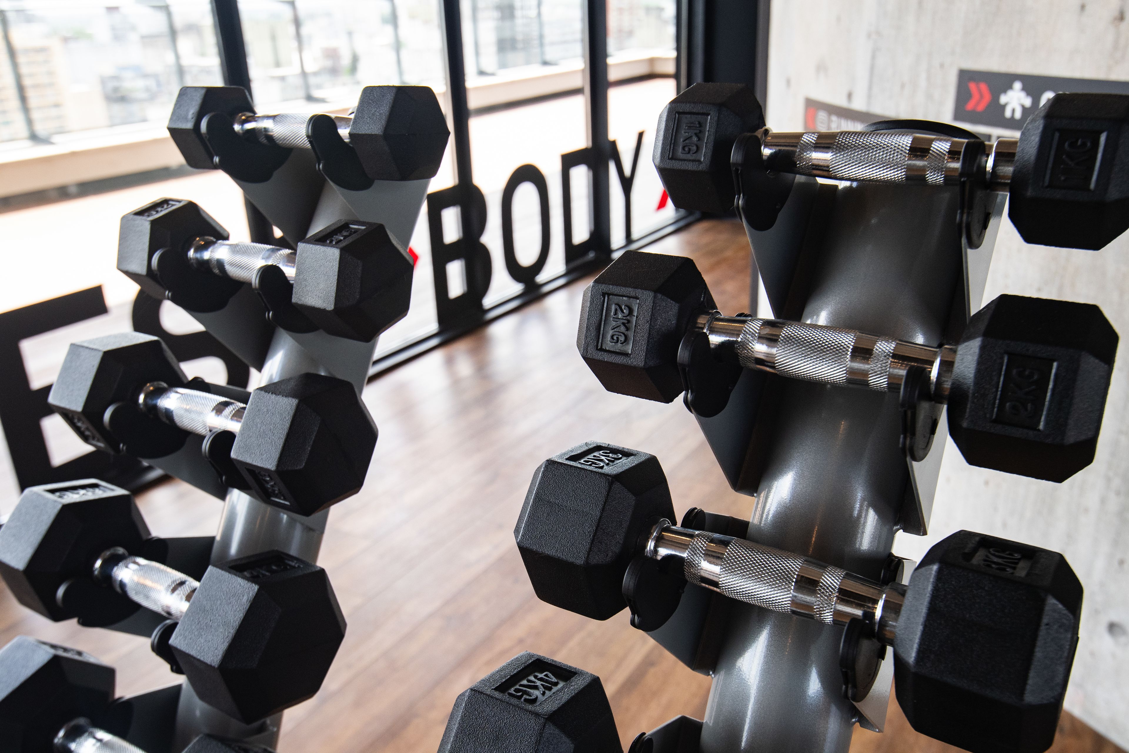 Ett gym med olika typer av hantlar och en skylt med texten ”BODY”.