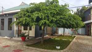 A courtyard with a large tree, potted plants, and a paved walkway. - Perfect Home Two minutes to Kijiji Beach (Dar es Salaam)
