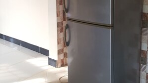 A kitchen with a stainless steel refrigerator, tiled backsplash, and a framed picture on the wall. - Perfect Home Two minutes to Kijiji Beach (Dar es Salaam)