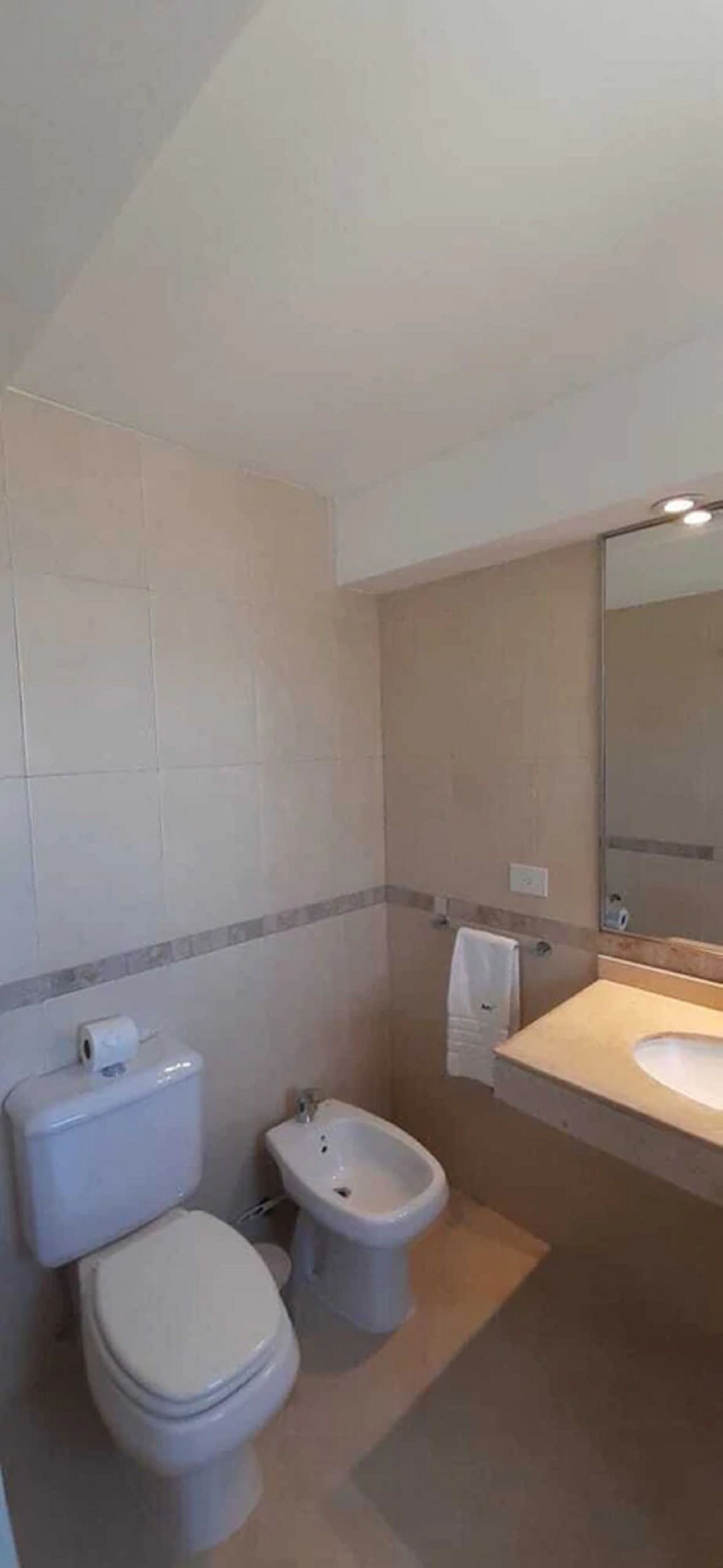 A bathroom with a toilet, bidet, and sink.