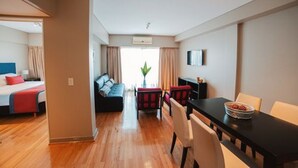 A hotel room with a bed, a sofa, a dining table, and a small kitchen area. - ARC Callao Studios & Suites (Buenos Aires)